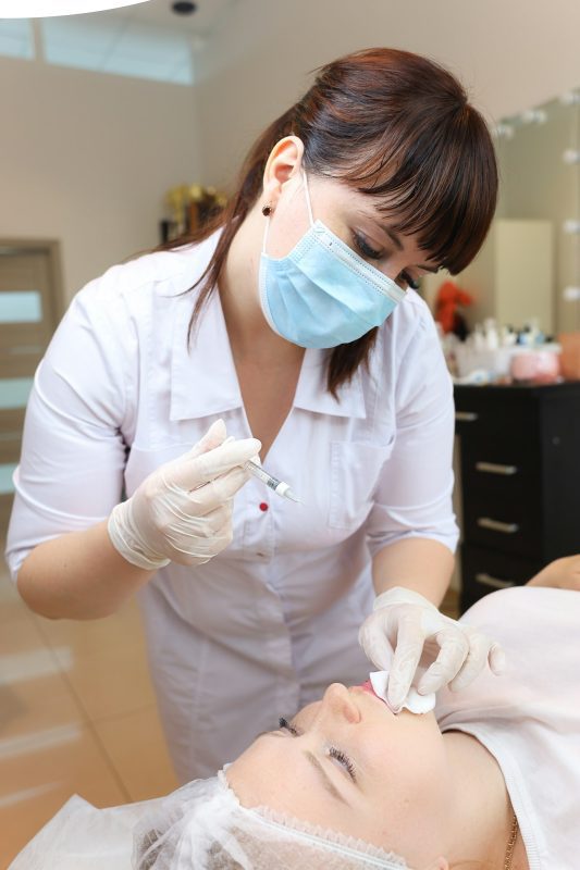The beautician holds syringes for injections of hyaluronic
